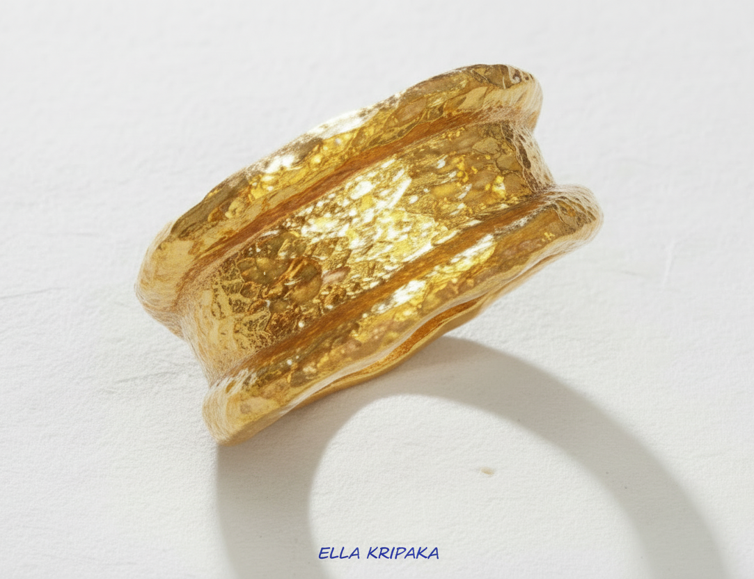 Organic hammered 24k 9999 Gold ring with thick uneven edges on white paper surface, artist-jeweler's name 'Ella Kripaka' is written in picture