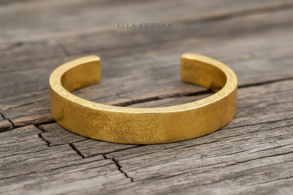 Hammered 24k 9999 Gold thick cuff bracelet Ancient Rome style on a wooden background with 'Ella Kripaka' branding