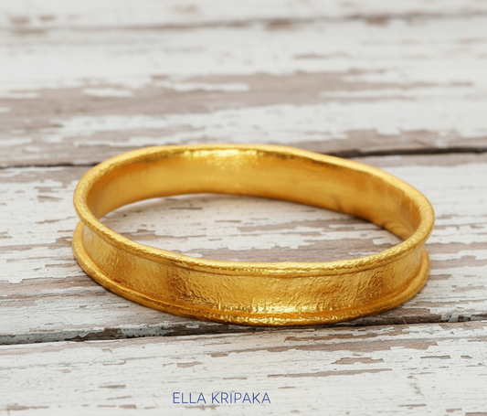 Hammered 24k 9999 Gold thick bangle bracelet Ancient Rome style on old white wooden surface, artist's name 'Ella Kripaka' branding