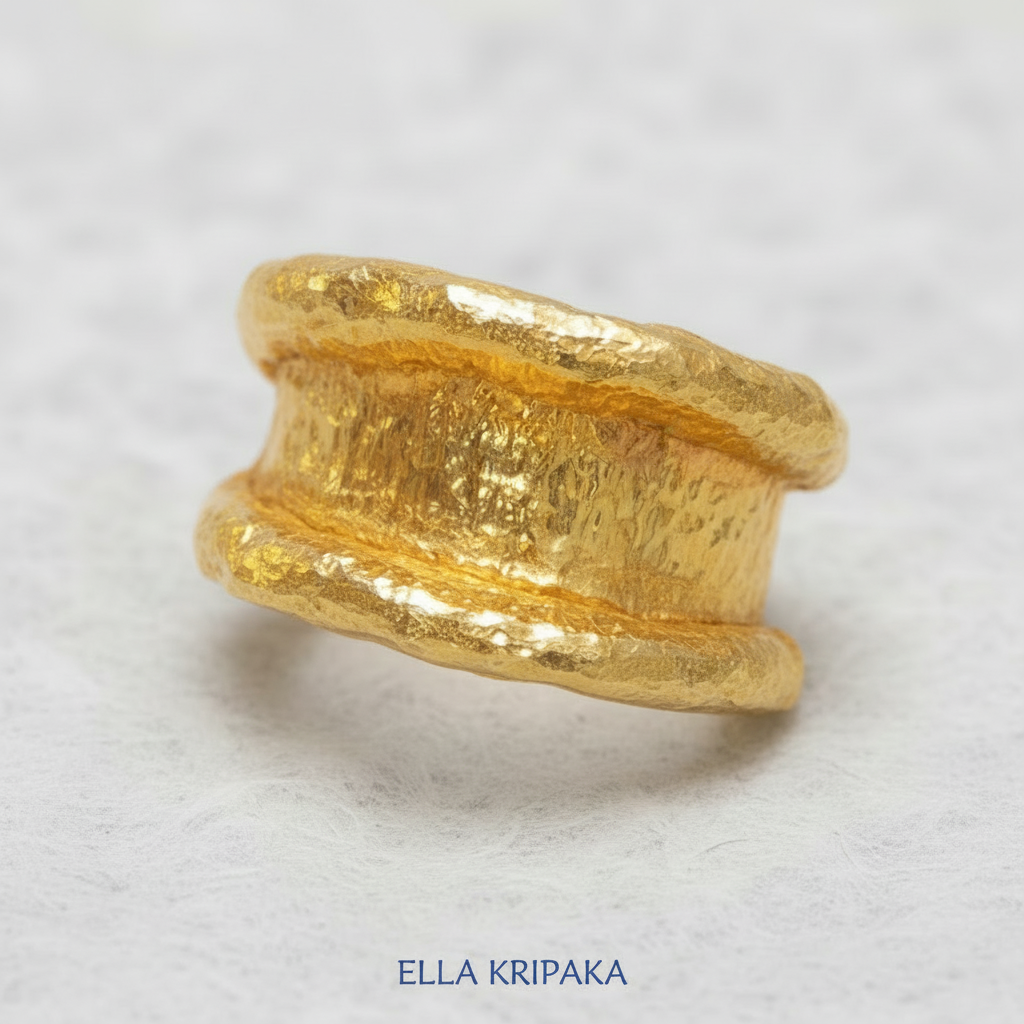 Organic hammered 24k 9999 Gold ring with thick uneven edges on white paper surface, artist-jeweler's name 'Ella Kripaka' is written in picture