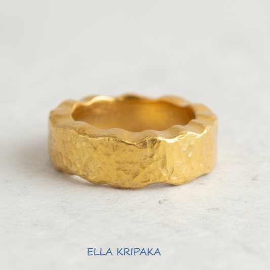 Organic hammered 24k 9999 Gold wavy ring band with thick wavy edges and with forged gold textures on white paper surface, artist-jeweler's name 'Ella Kripaka' branding