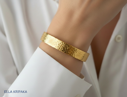 24k 9999 gold thick hammeted bracelet cuff worn on a woman's wrist with a white shirt background