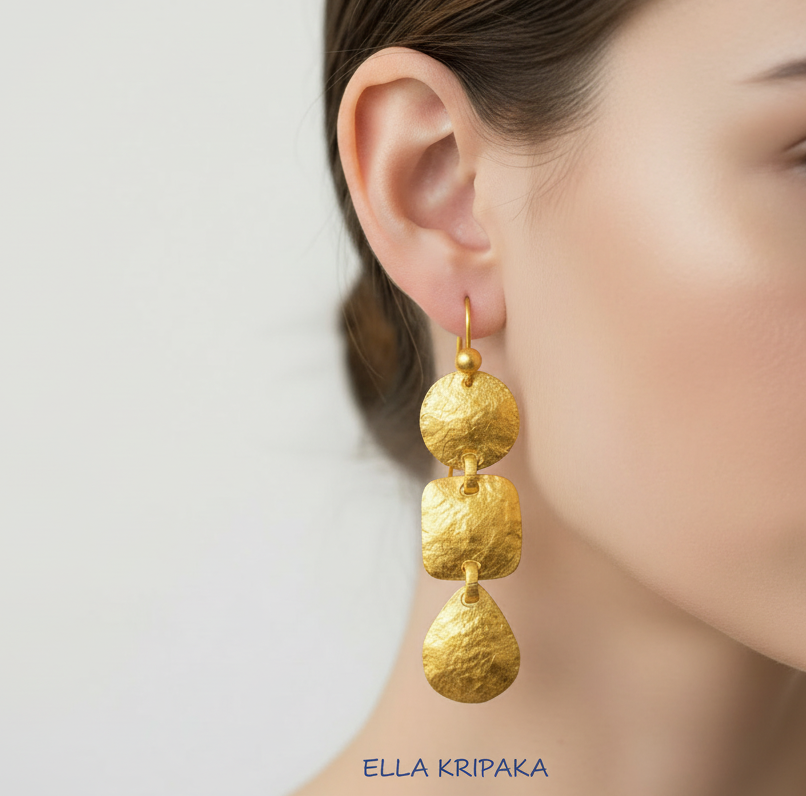 Hammered 24k 9999 gold Byzantine convex earrings worn by a person on a plain background, artist's name branding 'Ella Kripaka'