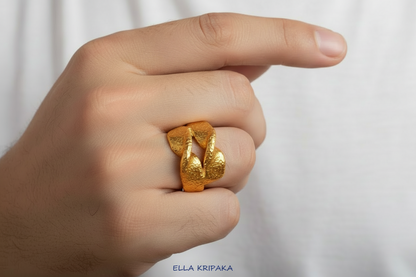 Twisted hammered 24k 9999 Gold ring signet with textured gold worn on person's finger and on a white surface, artist-jeweler's name 'Ella Kripaka' is written on picture