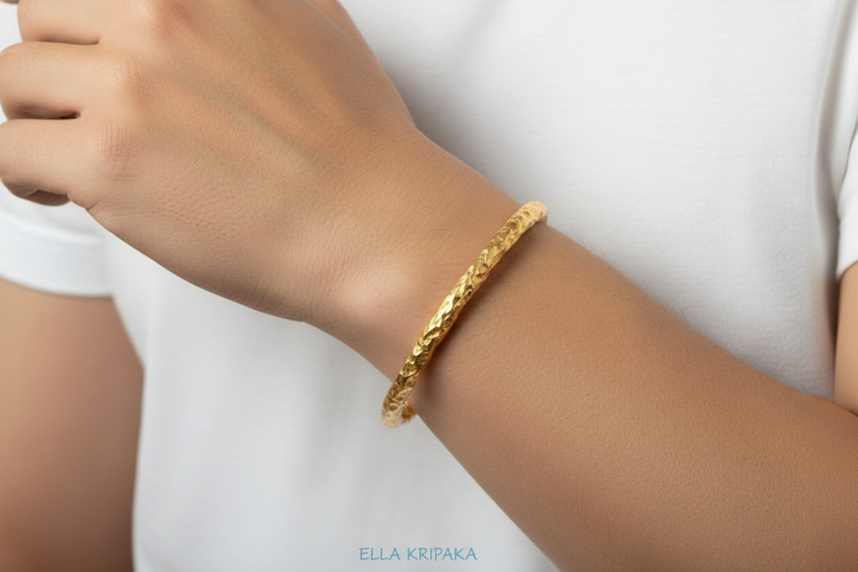 Organic hammered 24k 9999 gold bracelet uneven bangle worn on hand by a man and on white background, branding artist-jeweler name 'Ella Kripaka'