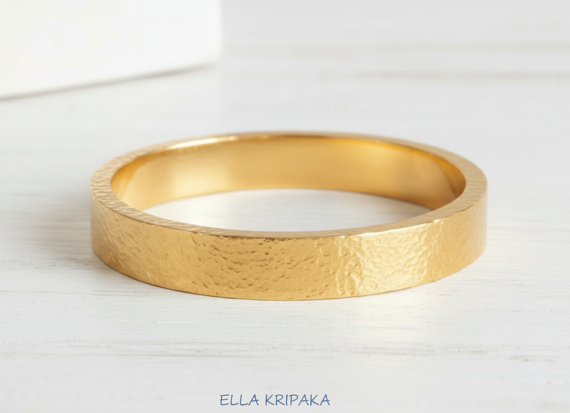 Hammered 24k 9999 Gold thick bangle bracelet Ancient Rome style on white wooden surface, artist's name 'Ella Kripaka' branding