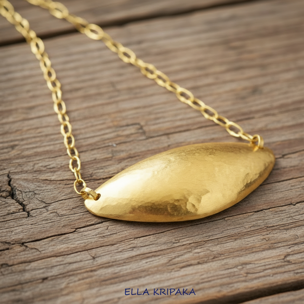 24k 9999 gold hammered dome pendant with forged gold textures and with chain is on a old wooden surface, artist's name 'Ella Kripaka'