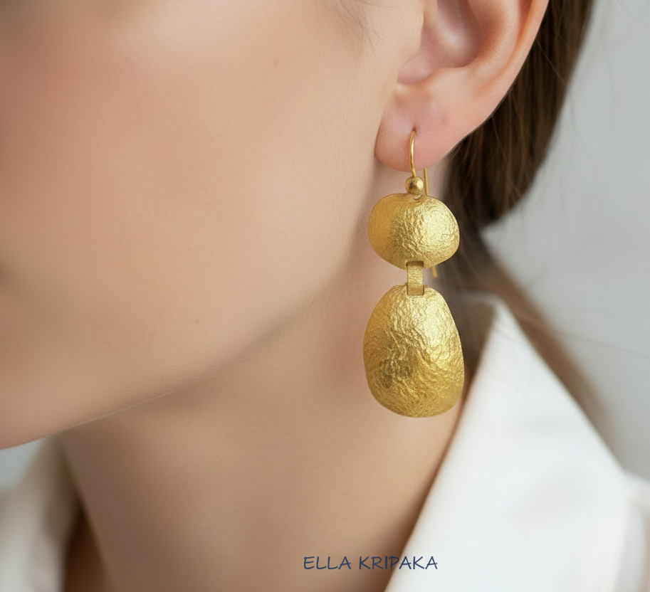 24k 9999 gold hammered convex organic earrings with forged gold textures is worn by person, artist's name 'Ella Kripaka'