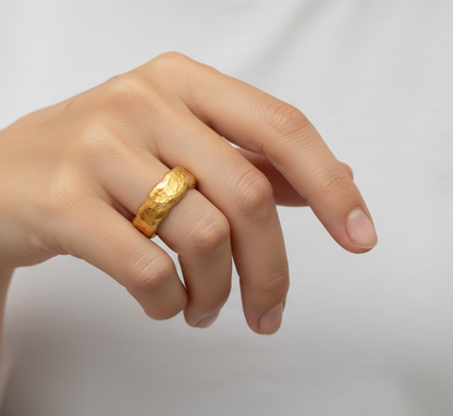 Organic hammered 24k 9999 gold wavy ring band and with forged gold textures worn on person's finger and on a white plain background, artist-jeweler's name 'Ella Kripaka' branding