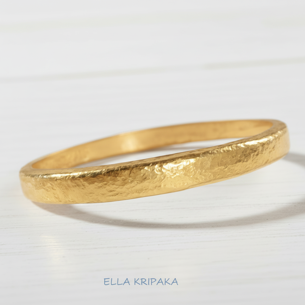 Hammered 24k gold 9999 gold bangle thick bracelet Ancient Rome style on a white wooden surface, artist-jeweler 'Ella Kripaka' branding