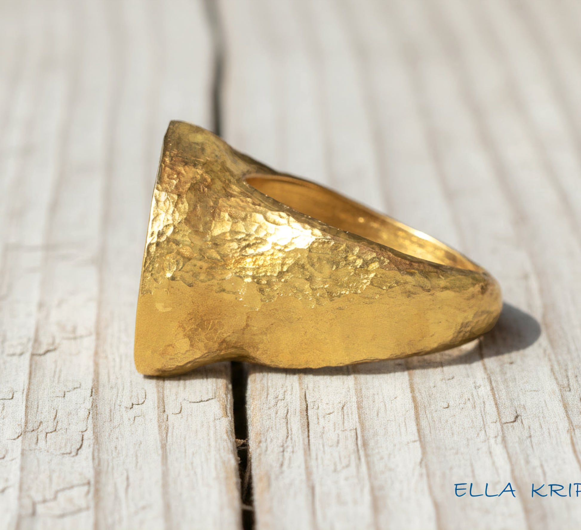 Hammered 24k 9999 Gold ring thick signet Ancient Egypt style and Ancient Rome style and with forged textured gold on a light old wooden surface, artist-jeweler's name 'Ella Kripaka' branding