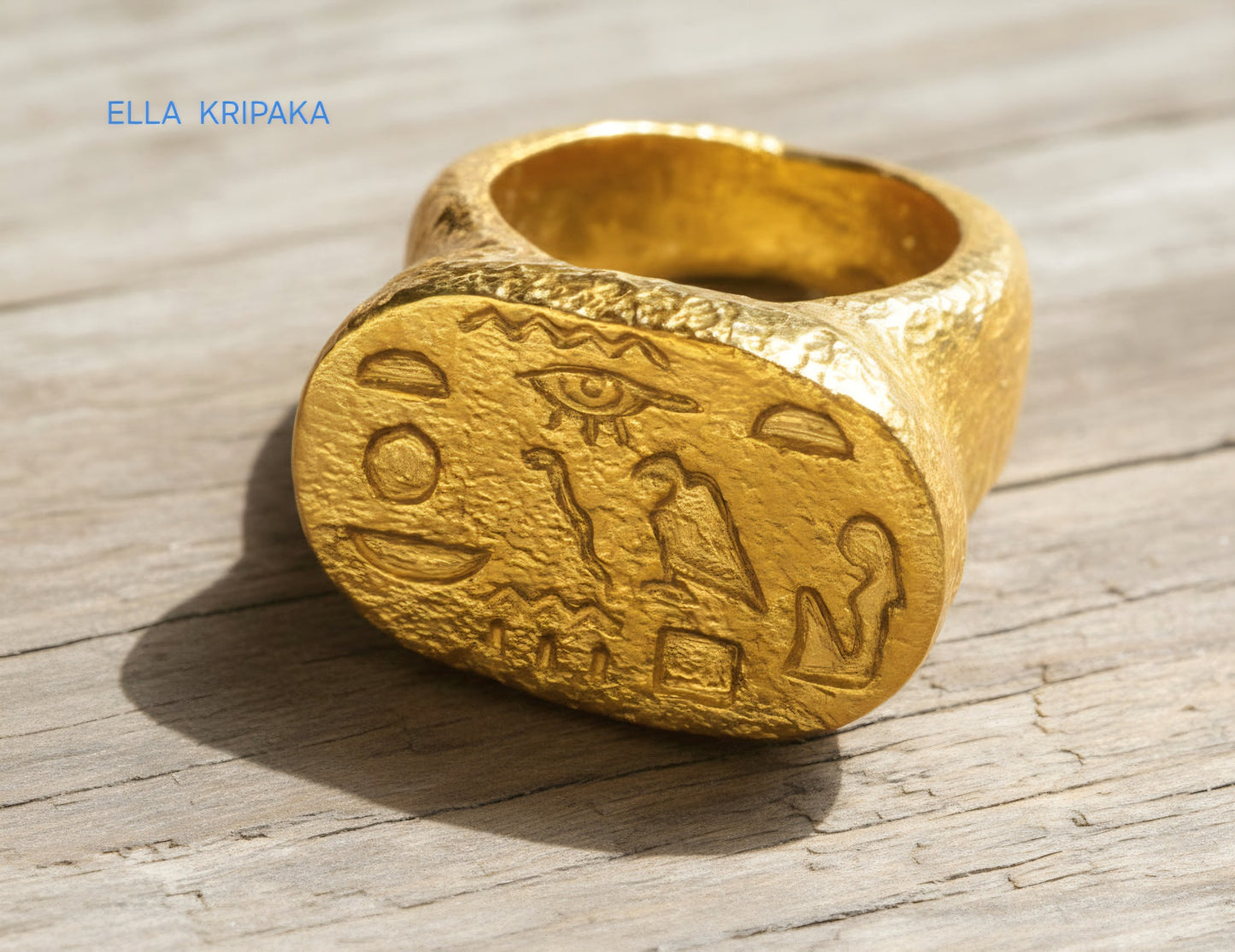 Hammered 24k 9999 Gold ring thick signet Ancient Egypt style and with forged textured gold on a light old wooden surface, artist-jeweler's name 'Ella Kripaka' branding