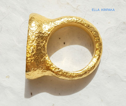 Hammered 24k 9999 Gold ring thick signet Ancient Egypt style and Ancient Rome style and with forged textured gold on a white paper surface, artist-jeweler's name 'Ella Kripaka' branding