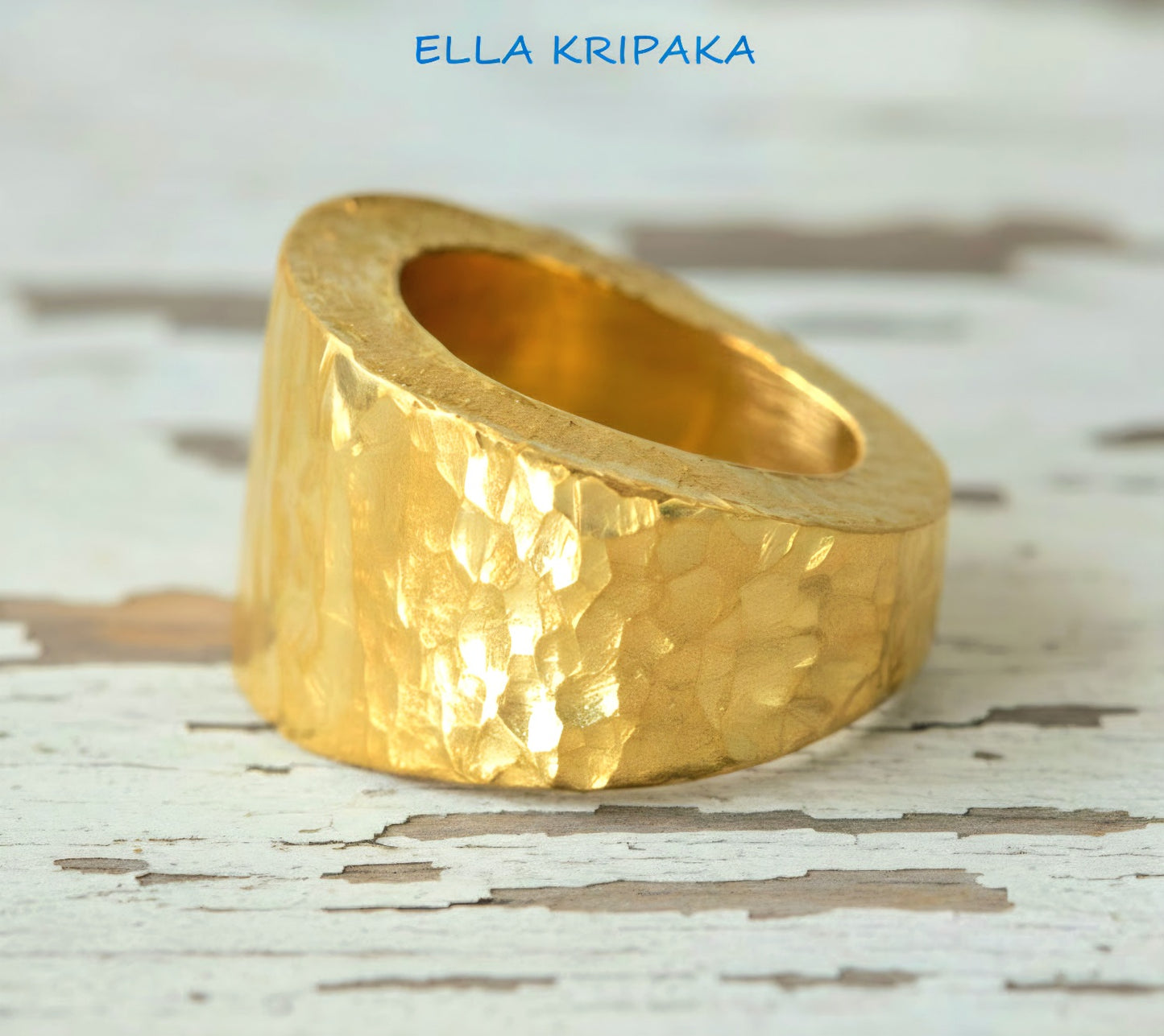 Hammered 24k 9999 Gold ring thick signet Ancient Rome style and with forged textured gold on a white old wooden surface, artist-jeweler's name 'Ella Kripaka' branding