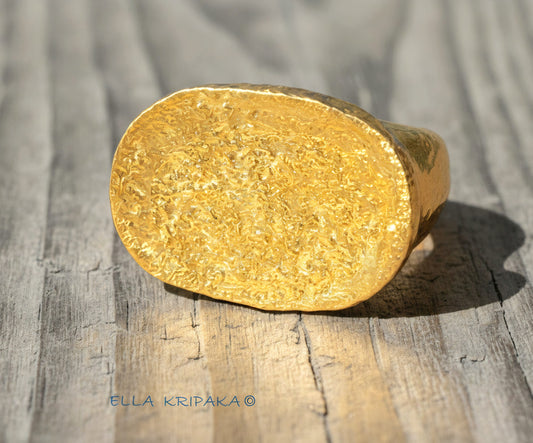 Hammered 24k 9999 Gold ring thick signet Ancient Egypt style and Ancient Rome style and with forged textured gold on a light old wooden  surface, artist-jeweler's name 'Ella Kripaka' branding