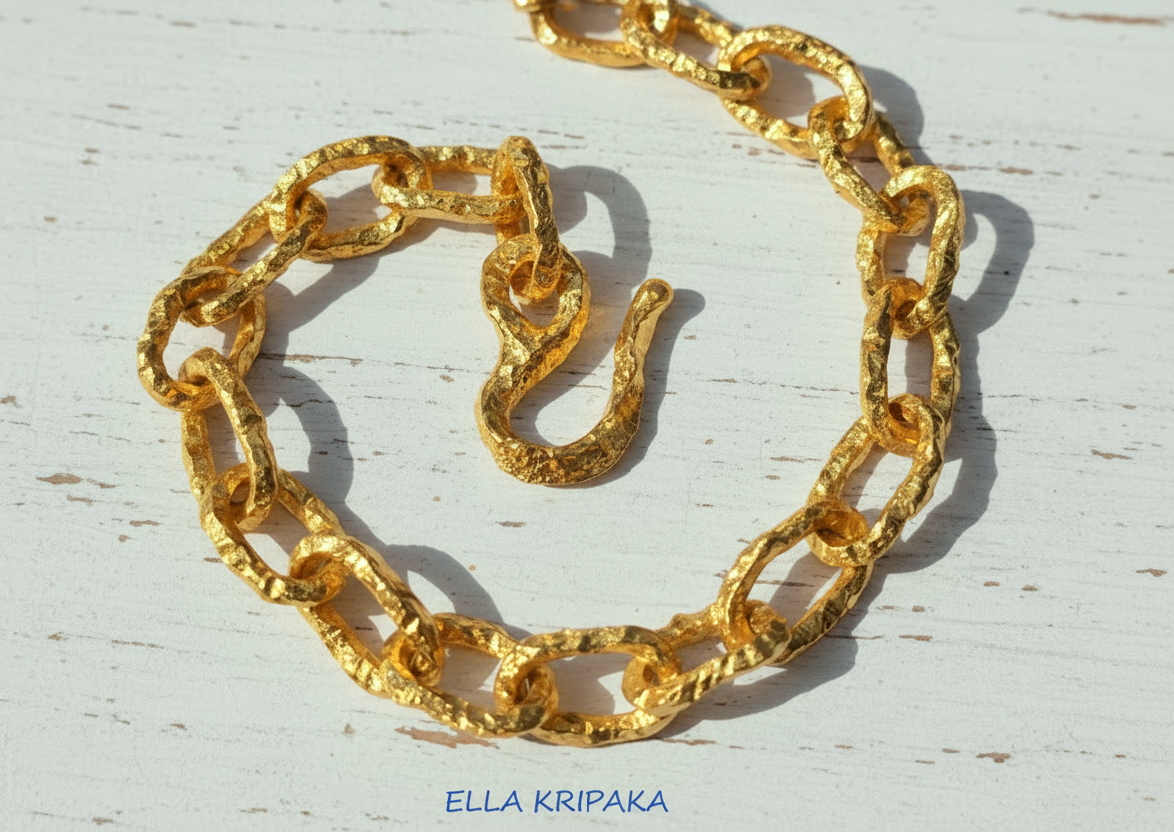 Hammered 24k 9999 gold organic necklace chain with hammered uneven textures and a thick hook clasp on white wooden surface, artist name 'Ella Kripaka'