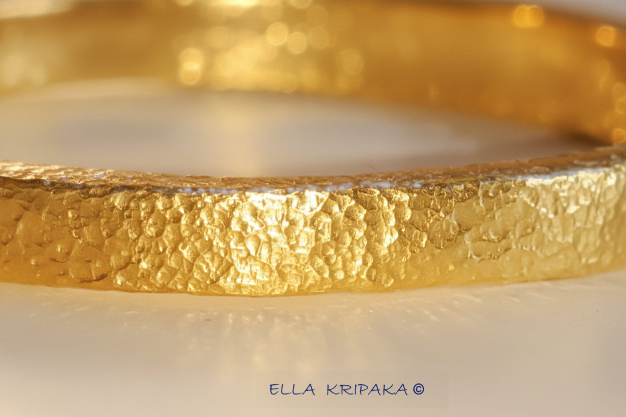 Hammered 24k Gold textured bangle bracelet on light surface, artist's name 'Ella Kripaka' branding
