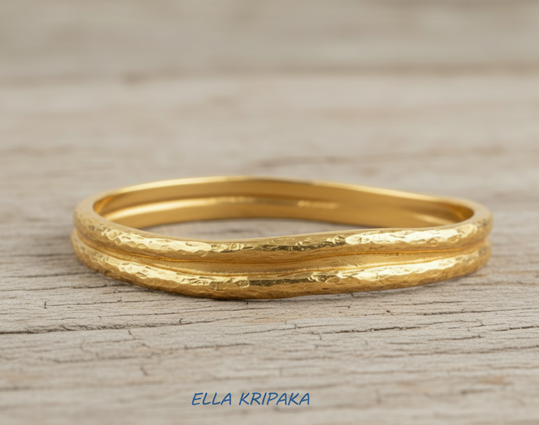 Organic 24k gold 9999 gold hammered bangle thick bracelet with uneven edges on wooden surface, name of artist-jeweler 'Ella Kripaka'