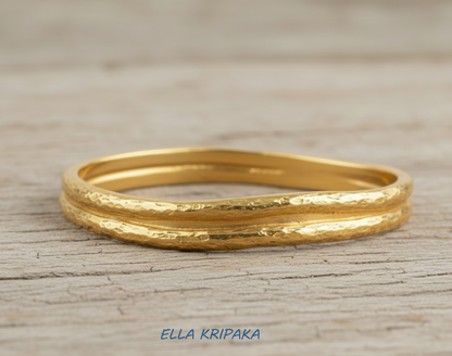 Organic 24k gold 9999 gold hammered bangle thick bracelet with uneven edges on wooden surface, name of artist-jeweler 'Ella Kripaka'