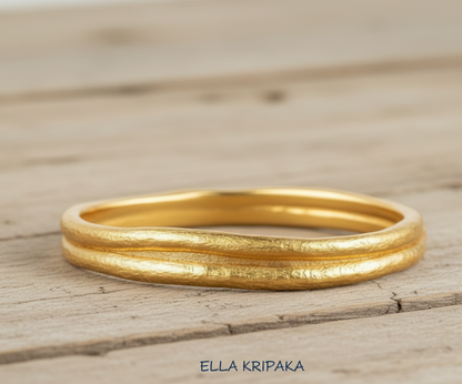 Organic 24k gold 9999 gold hammered bangle thick bracelet with uneven edges on wooden surface, name of artist-jeweler 'Ella Kripaka'
