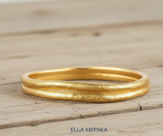 Organic 24k gold 9999 gold hammered bangle thick bracelet with uneven edges on wooden surface, name of artist-jeweler 'Ella Kripaka'