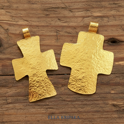 Two hammered 24k gold textured crosses pendants on a rustic wooden surface, artist-jeweler 'Ella Kripaka' branding
