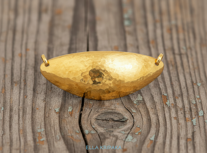 24k 9999 gold hammered dome pendant with forged gold textures is on a old wooden surface, artist's name 'Ella Kripaka'