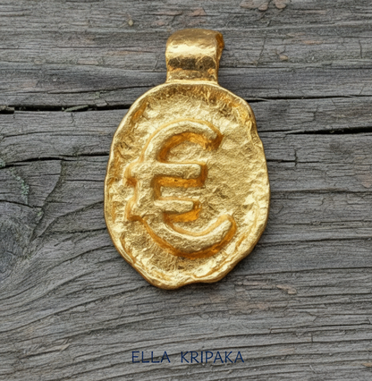 Organic 24k gold hammered uneven pendant with convex 'Euro' sign on a old wooden surface, branded artist 'Ella Kripaka'