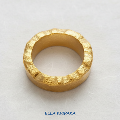 Organic hammered 24k 9999 Gold wavy ring band with thick wavy edges and with forged gold textures on white paper surface, artist-jeweler's name 'Ella Kripaka' branding