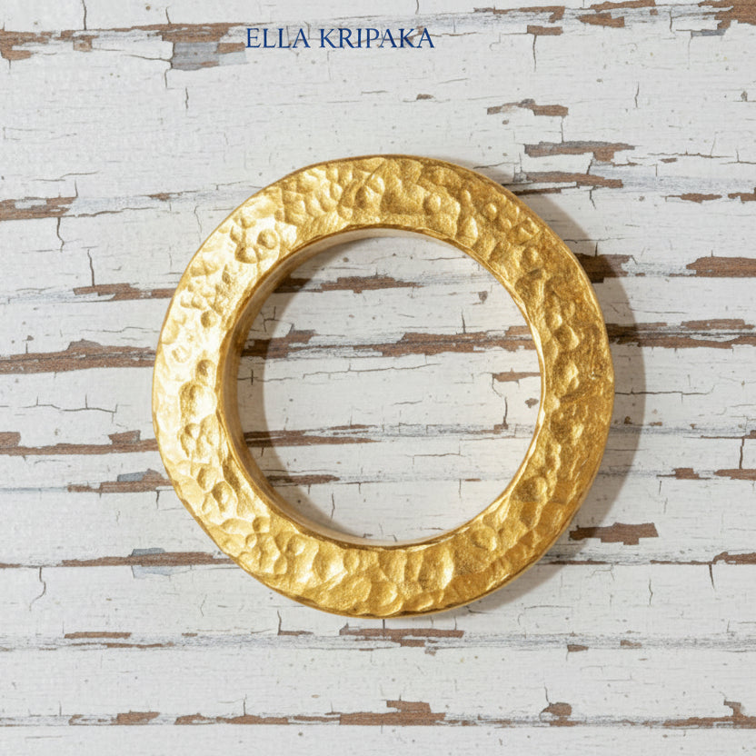 Hammered 24k 9999 Gold thick ring Ancient Rome style and with forged textured gold on a white old wooden surface, artist-jeweler's name 'Ella Kripaka' branding