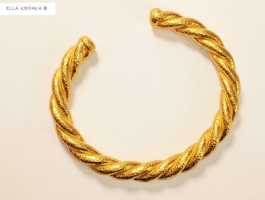 Twisted 24k gold hammered textured shiny cuff Viking Style on white paper background, and with artist 'Ella Kripaka' branding