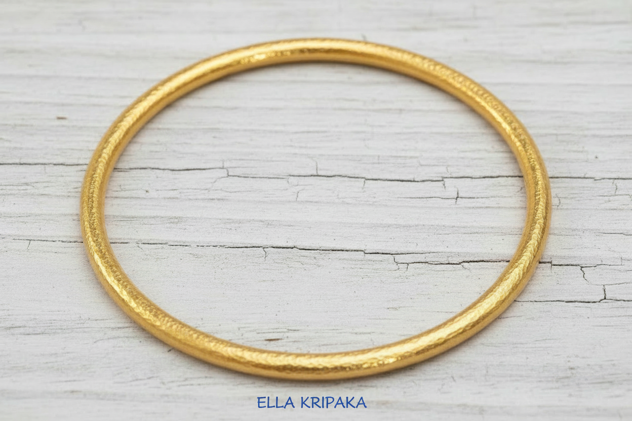 Hammered 24k 9999 gold bangle thick bracelet Ancient Rome style on old white wooden background, artist-jeweler's name 'Ella Kripaka'