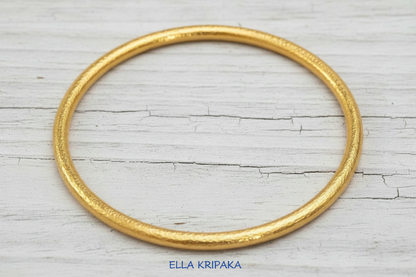 Hammered 24k 9999 gold bangle thick bracelet Ancient Rome style on old white wooden background, artist-jeweler's name 'Ella Kripaka'