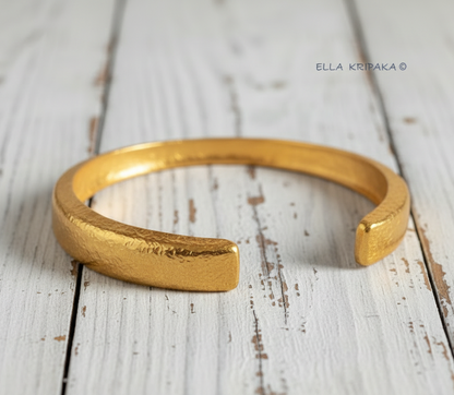 Hammered 24k 9999 gold bracelet cuff Ancient Rome style on a old white wooden background, branding artist-jeweler name 'Ella Kripaka'