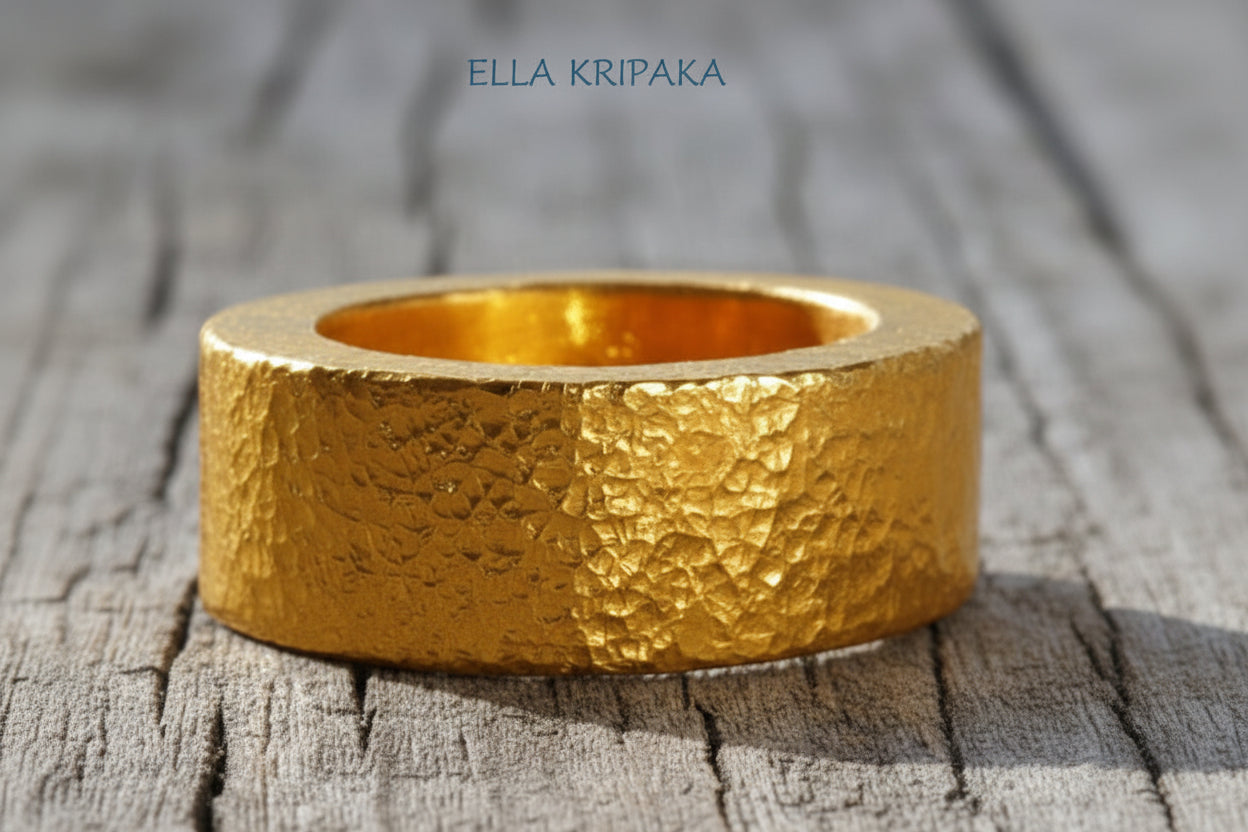 Hammered 24k Gold 9999 gold ring thick heavy and with textured surface on a grey wooden background, branded 'Ella Kripaka'