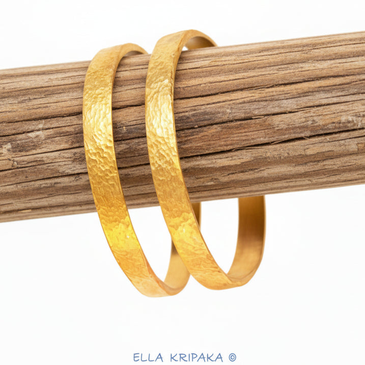 Hammered 24k 9999 gold two bangles thick bracelets Ancient Rome style on a rustic wooden stand, branding artist-jeweler name 'Ella Kripaka'