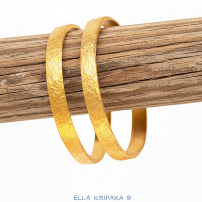 Hammered 24k 9999 gold two bangles thick bracelets Ancient Rome style on a rustic wooden stand, branding artist-jeweler name 'Ella Kripaka'