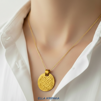 Organic hammered 24k gold, pure 9999 gold disk pendant on chain worn by a model and with white shirt and on grey background, artist-jeweler 'Ella Kripaka' branding