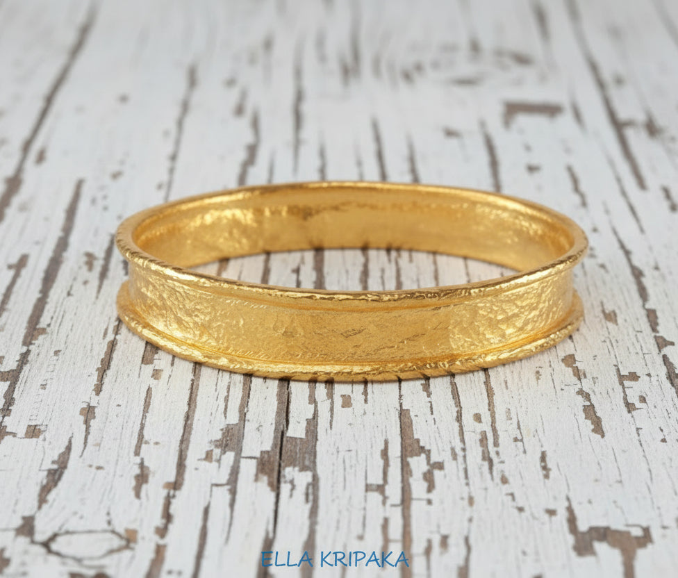 Hammered 24k 9999 Gold thick bangle bracelet Ancient Rome style on old white wooden surface, artist's name 'Ella Kripaka' branding