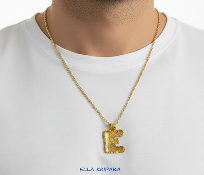 24k Gold necklace chain with organic initial letter 'E' pendant on a perdon in a white t-shirt, branded 'Ella Kripaka'.