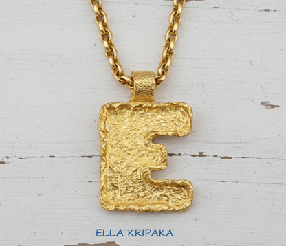 Gold necklace with hammeted organic 24k 9999 gold initial letter 'E' pendant on a white background, branded 'Ella Kripaka'