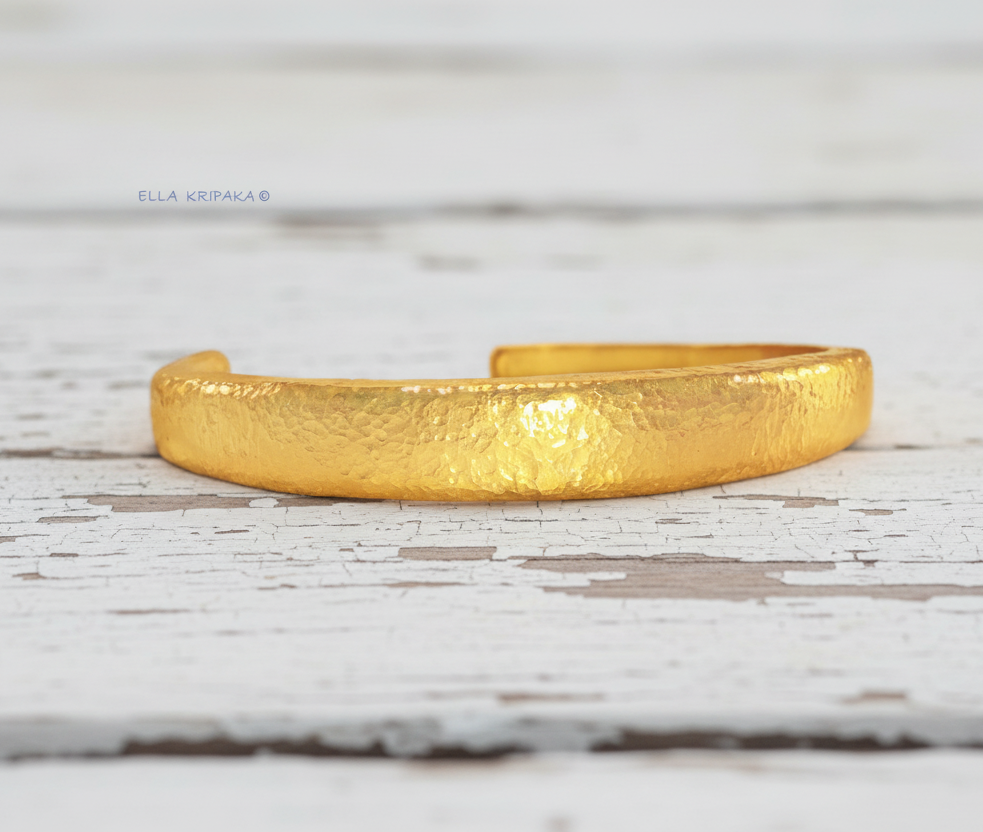Hammered 24k 9999 Gold thick cuff bracelet Ancient Rome style on a white wooden background with 'Ella Kripaka' branding