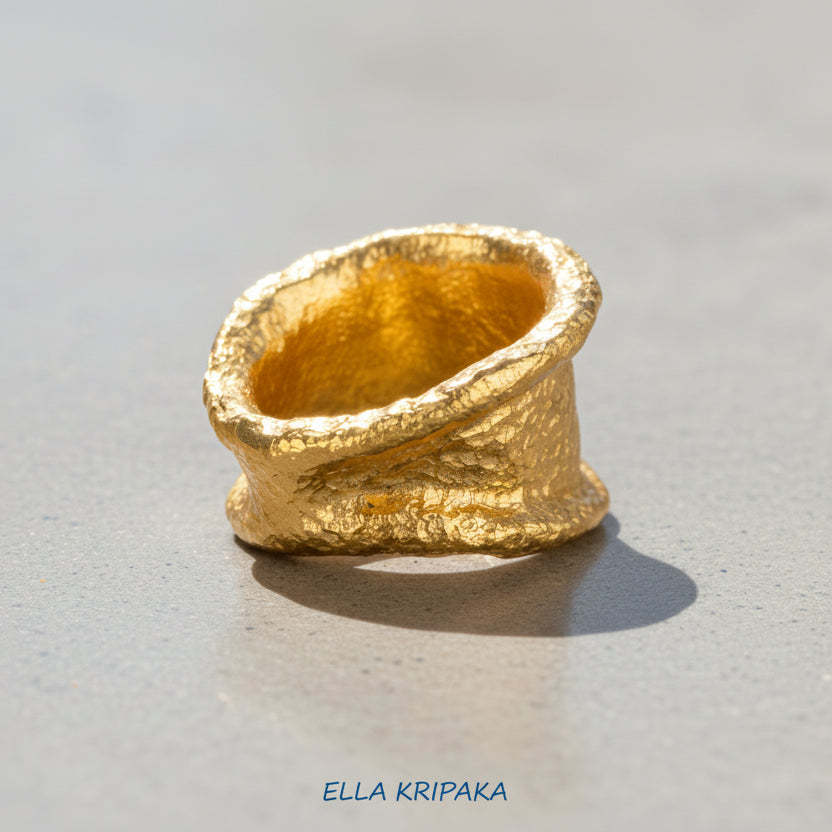 Organic hammered 24k 9999 gold ring signet with uneven thick edges on grey surface, artist-jeweler's name 'Ella Kripaka' is written in picture