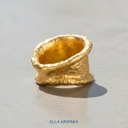 Organic hammered 24k 9999 gold ring signet with uneven thick edges on grey surface, artist-jeweler's name 'Ella Kripaka' is written in picture