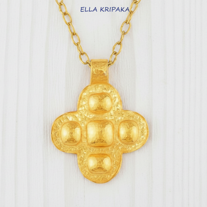 24k 9999 gold hammered Byzantine cross pendant with forged gold textures is on a white wooden surface, artist's name 'Ella Kripaka'