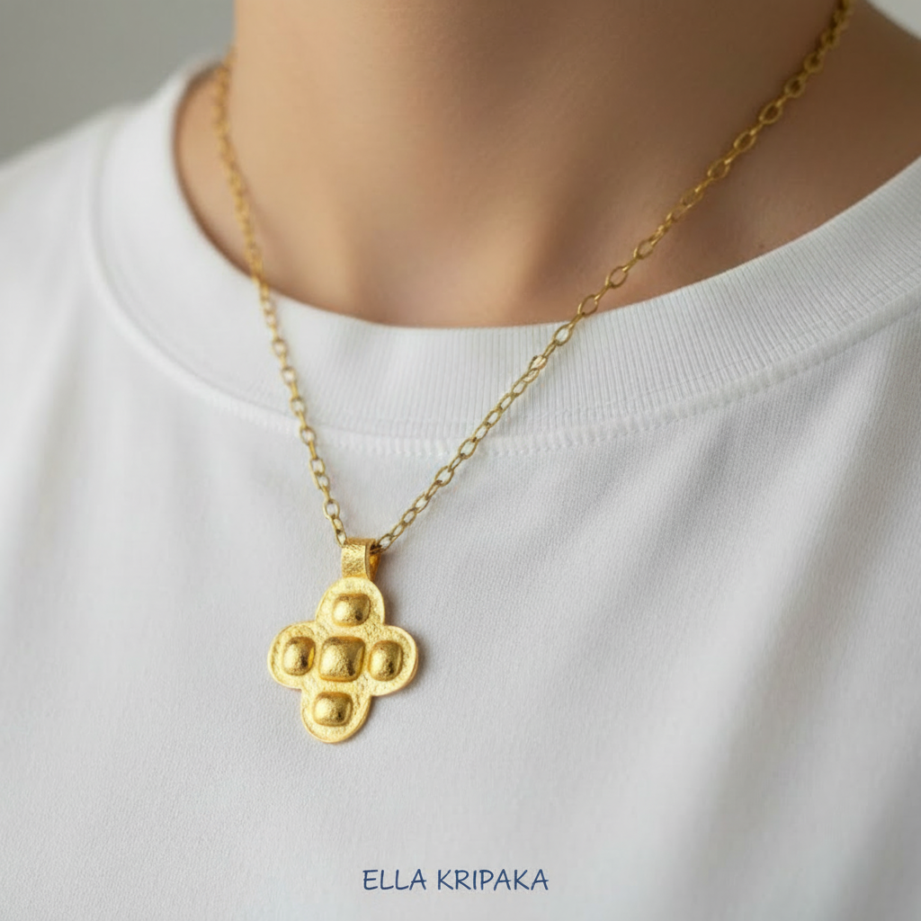 24k 9999 gold hammered Byzantine cross pendant on chain is wearing on person in a white t-shirt, artist's name 'Ella Kripaka'