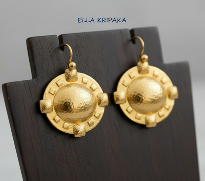 24k 9999 gold hammered Byzantine Cross earrings with forged gold textures is on a wooden stand, artist's name 'Ella Kripaka'