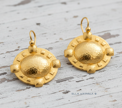 24k 9999 gold hammered Byzantine Cross earrings with forged gold textures is on a old wooden surface, artist's name 'Ella Kripaka'