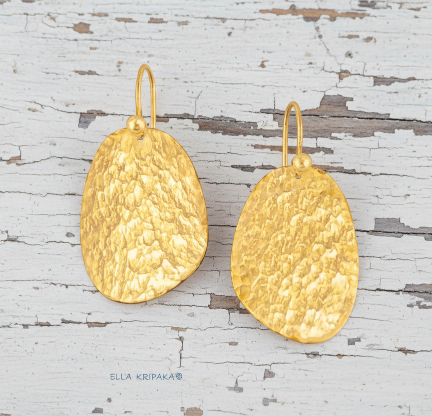 24k 9999 gold hammered organic earrings with forged gold textures is on a old white wooden surface, artist's name 'Ella Kripaka'