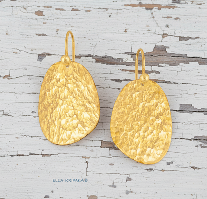 24k 9999 gold hammered organic earrings with forged gold textures is on a old white wooden surface, artist's name 'Ella Kripaka'